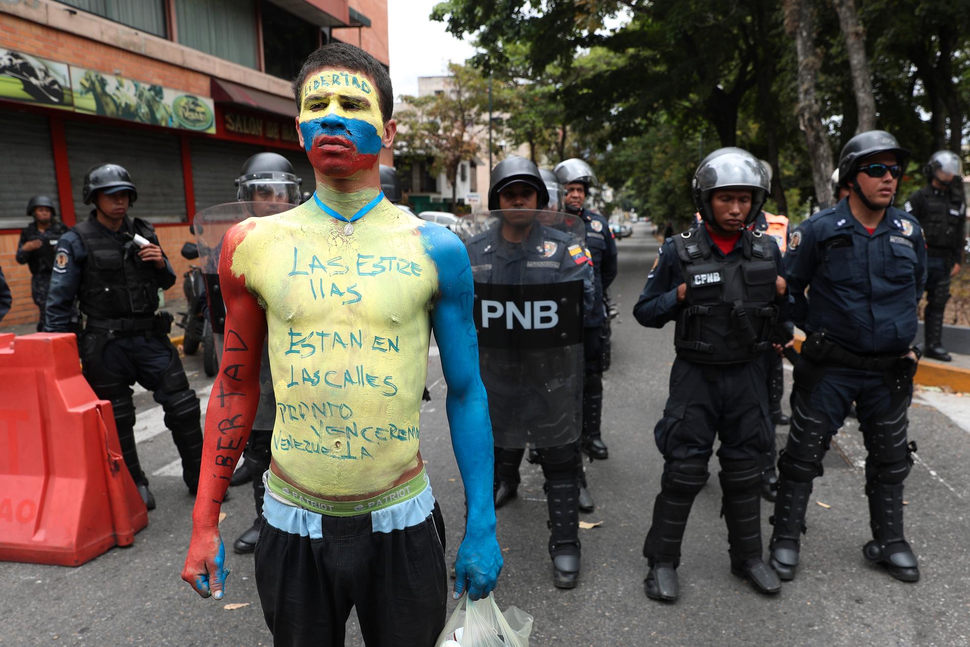 FN ska utreda människorättsbrott i Venezuela. Här demonstrerar en Maduro-motståndare framför poliser i huvudstaden Caracas i maj i år. Arkivbild.