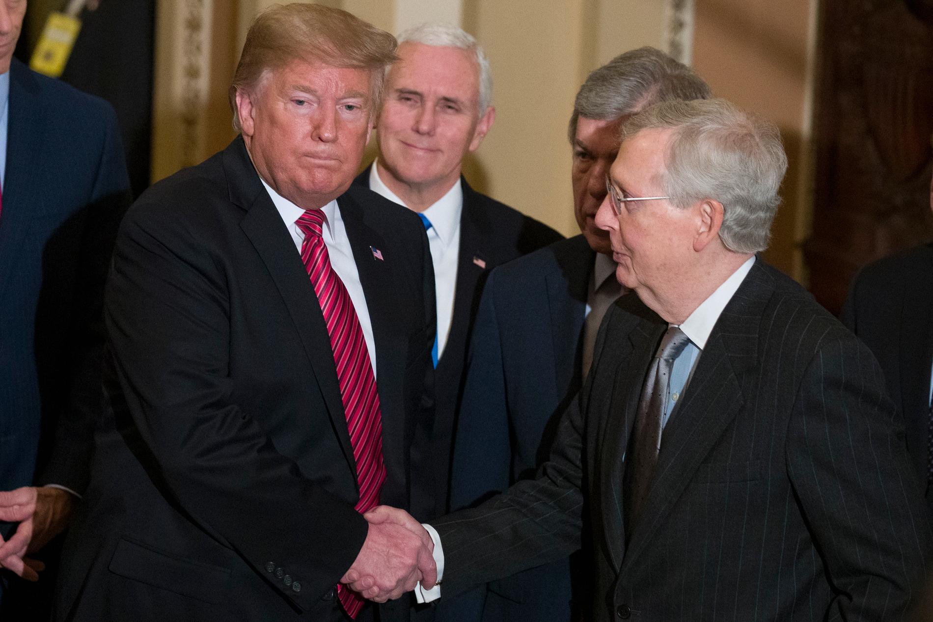 USA:s president Donald Trump skakar hand med senatens majoritetsledare, partikamraten Mitch McConnell. I bakgrunden syns vicepresident Mike Pence.
