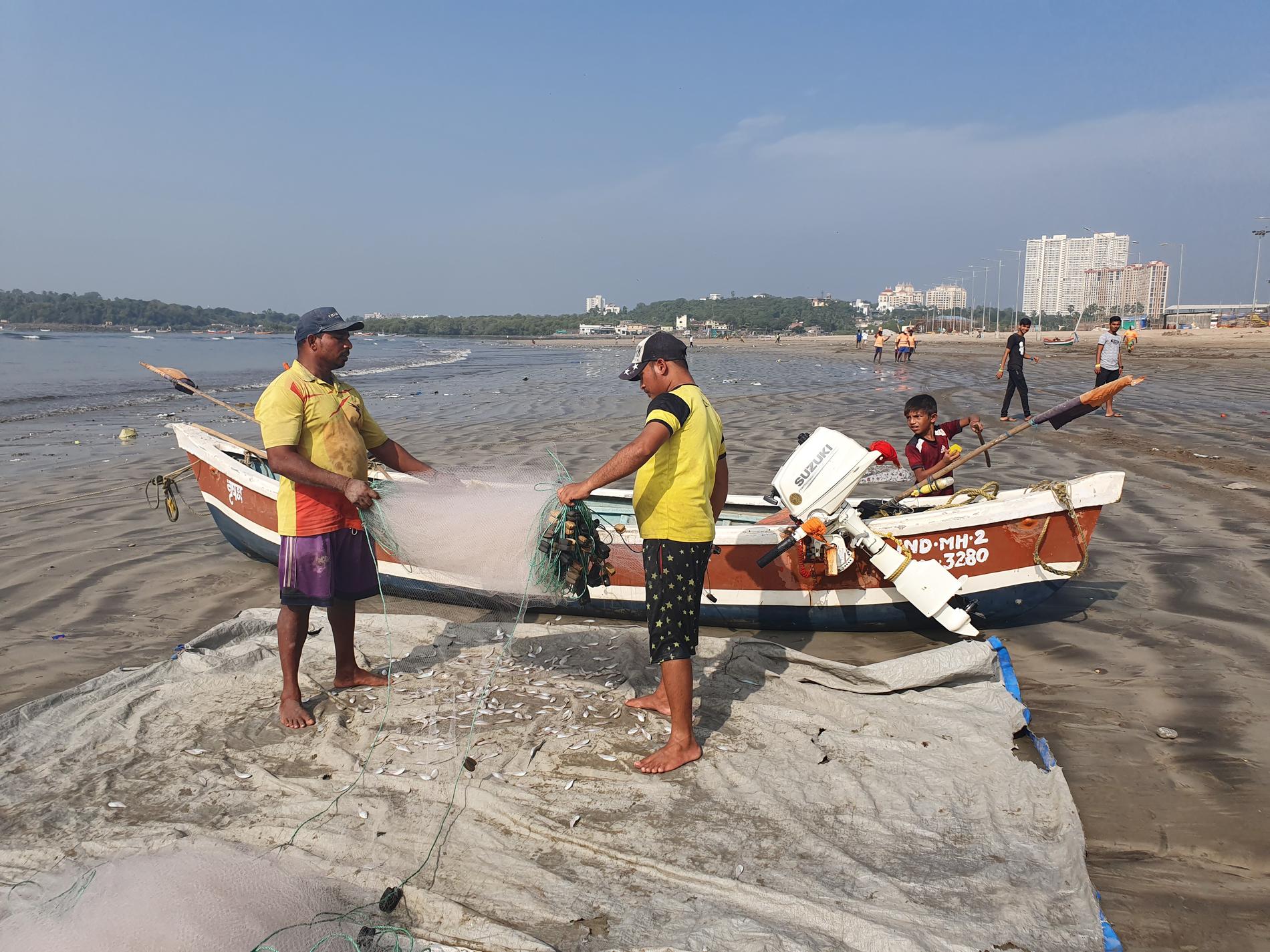 Versova beach i Mumbai. Fiskare tömmer sina nät några hundra meter bortom den iscensatta städdagen.