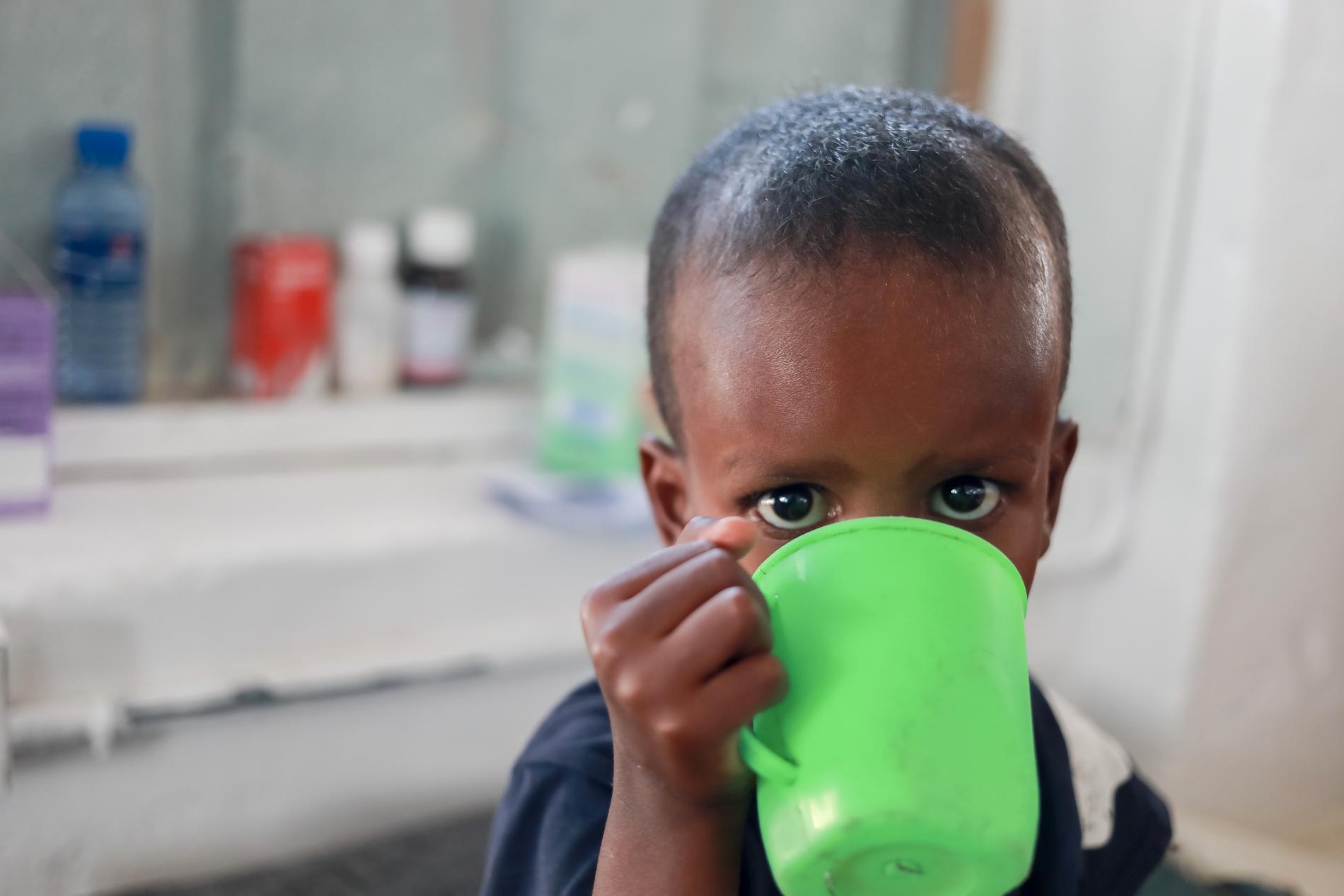 Ett litet barn får dricka i lägret utanför Kismayo.