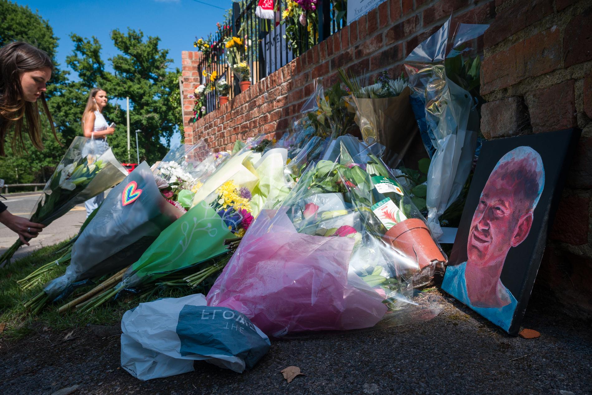 En student lägger blommor vid en minnesplats framför Holt skolans port för att  hedra sin lärare James Furlong som mördades vid attacken i Reading.