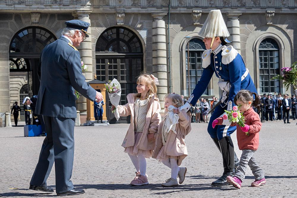 Kungen tar emot blommor och gratulationer från barn på slottets borggård. De minsta fich en hjälpande hand av en soldat från livgardet.