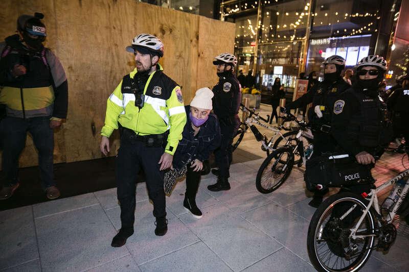 En kvinna tar skydd bakom polisen när Trumpsupportrar passerar.