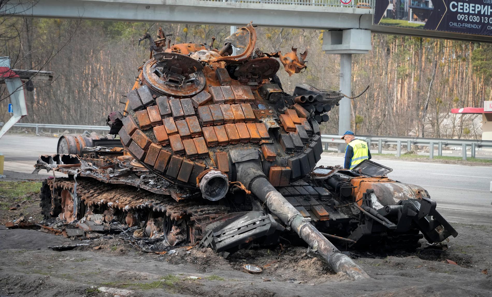 En ukrainsk funktionär undersöker en utbränd rysk stridsvagn vid en motorväg utanför Kiev i början av april.
