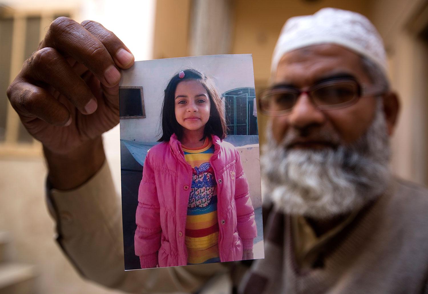 Mohammed Amin håller upp en bild på sin mördade dotter, Zainab Ansari, 7. 
