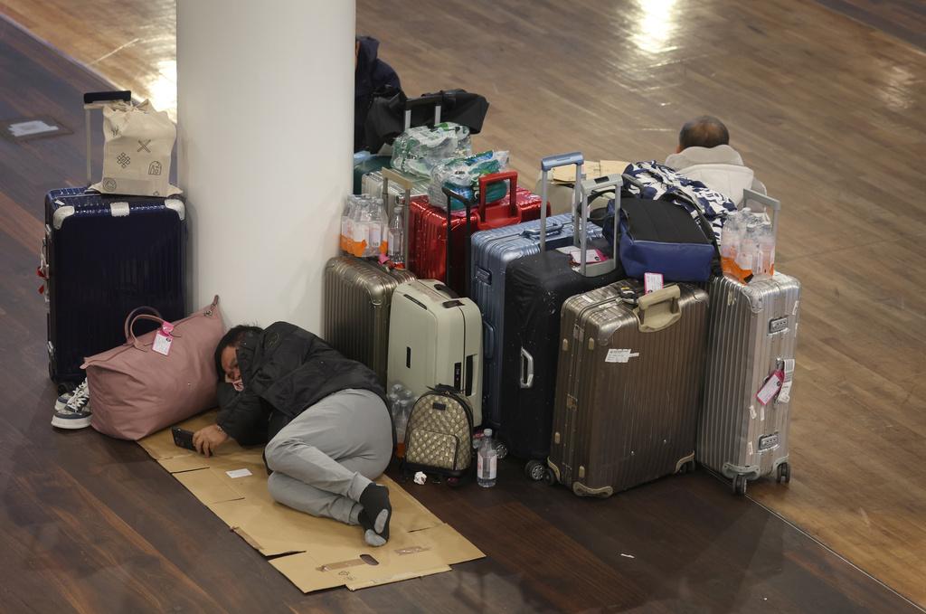 En passagerare sover i väntan på Münchens flygplats, som har stängts på grund av snön. 