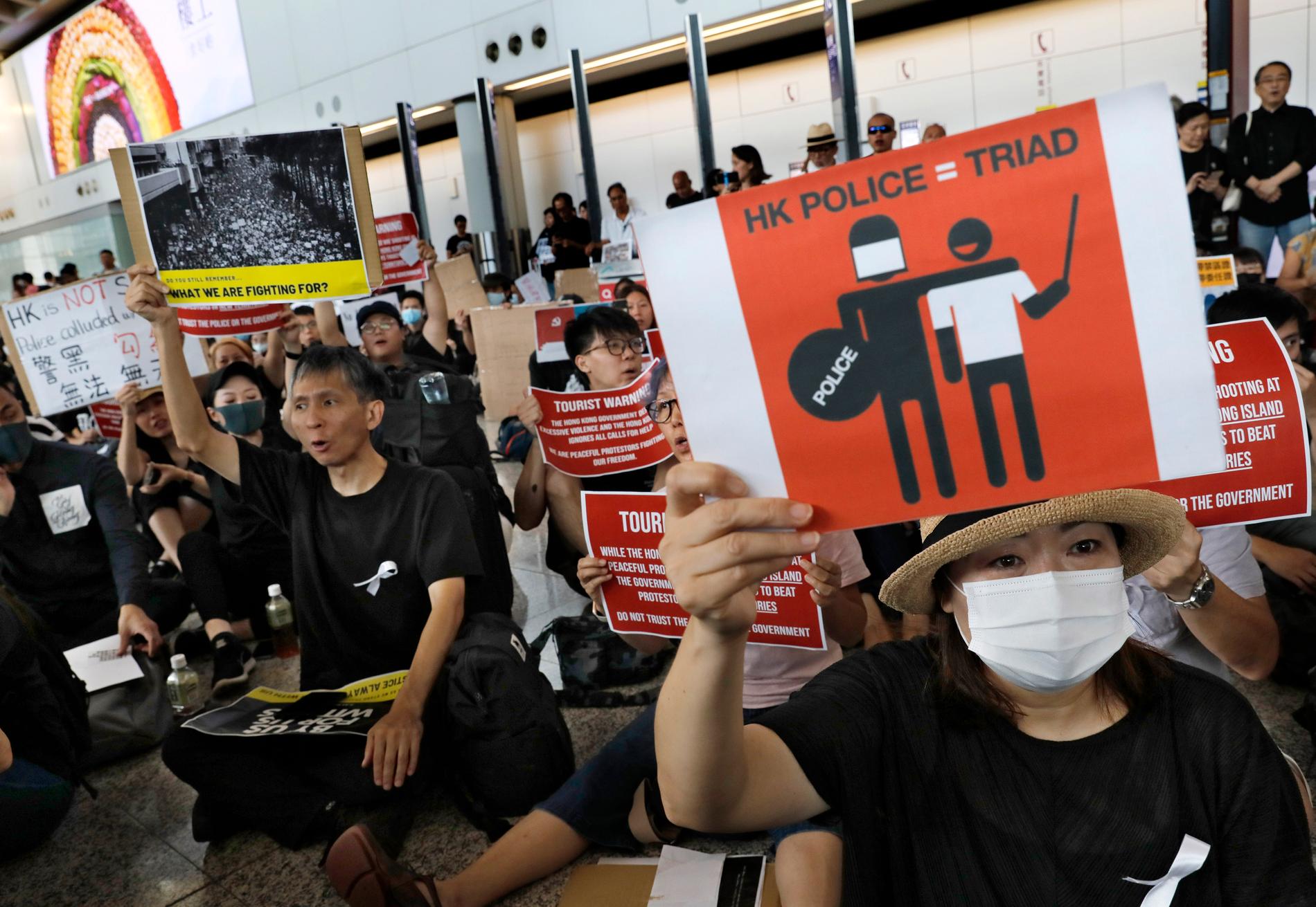 Demonstranter håller upp plakat under en protest på Hongkongs flygplats.