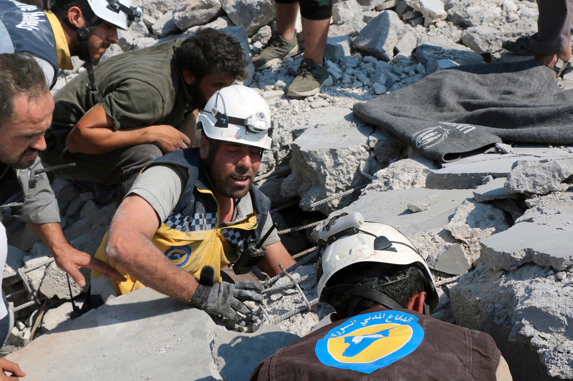Medlemmar av den syriska organisationen Vita hjälmarna arbetar vid en byggnad i byn Deir al-Sharqi som raserats i en flygattack på lördagen. Bildens äkthet har autentiserats av nyhetsbyrån AP.