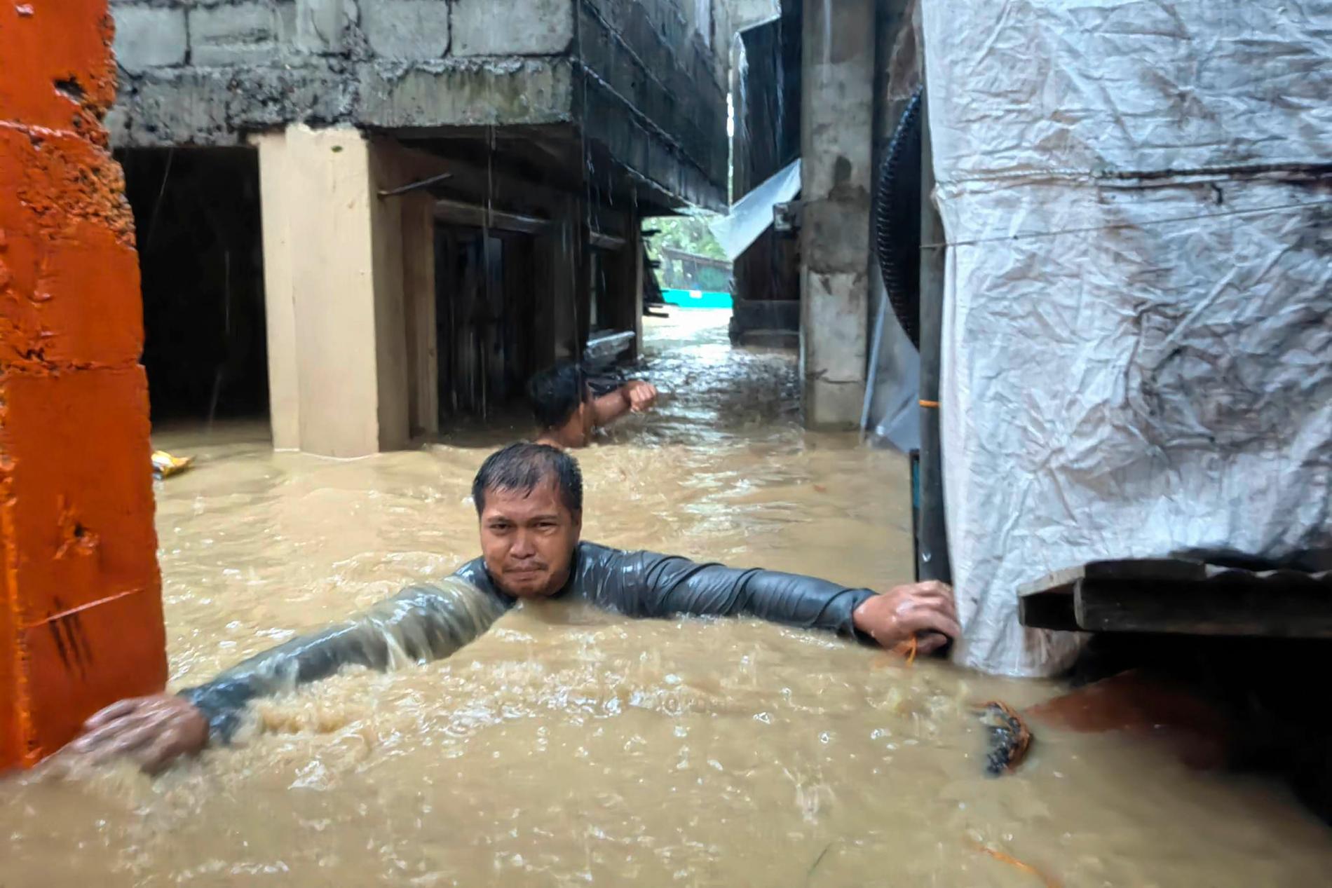 En man i Laoag city i Filippinerna kämpar sig genom vattenmassorna.