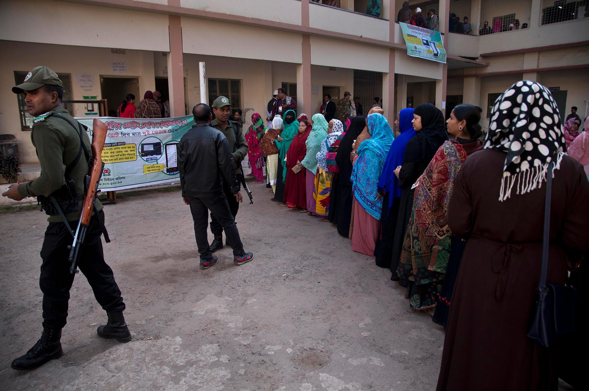 Säkerhetspersonal och köande väljare i Dhaka, Bangladesh.