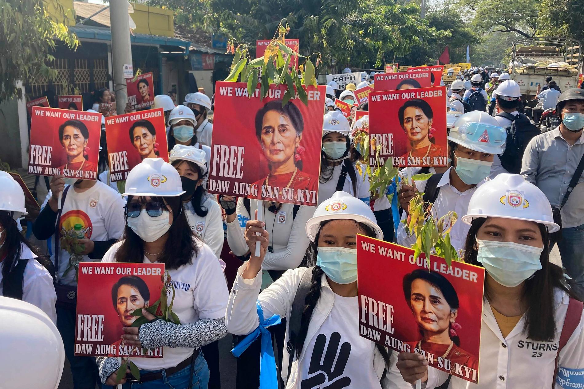 Demonstranter håller upp bilder av den avsatta cila ledaren Aung San Suu Kyi vid fredagens protester i Mandalay.