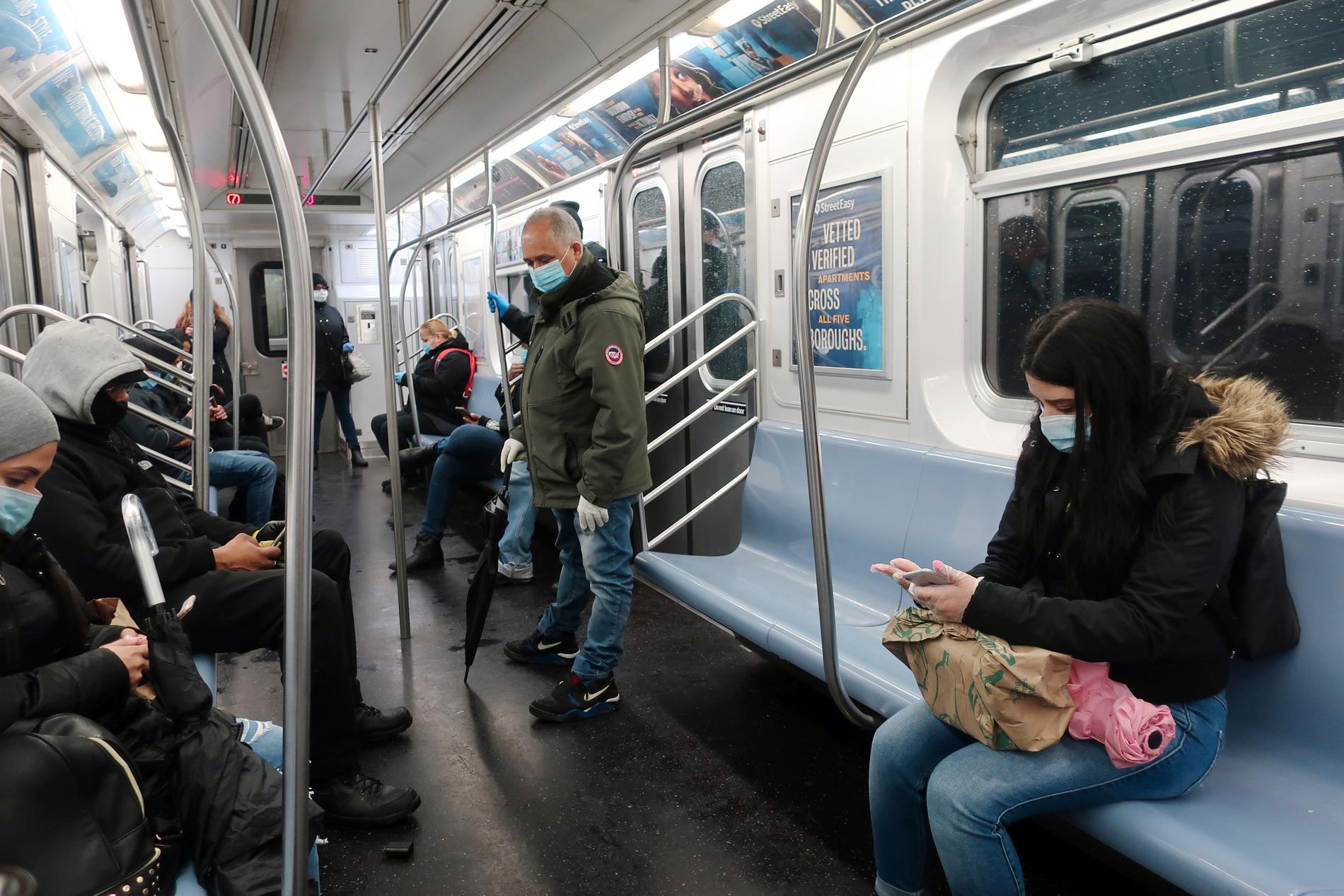 Människor med munskydd håller avstånd från varandra i tunnelbanan i det coronavirusdrabbade New York i USA.