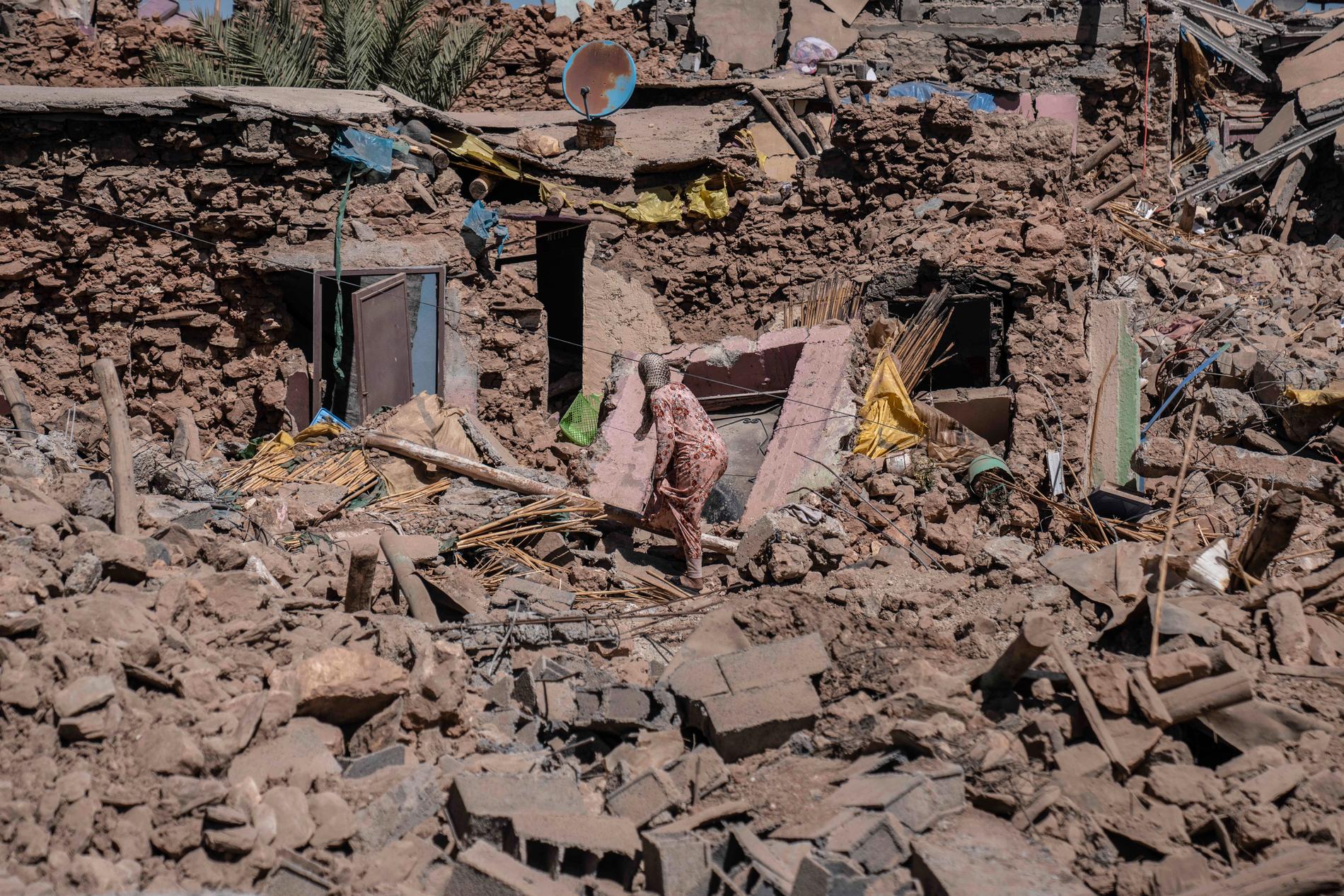 En kvinna försöker samla ihop sina tillhörigheter i resterna av hennes hus.