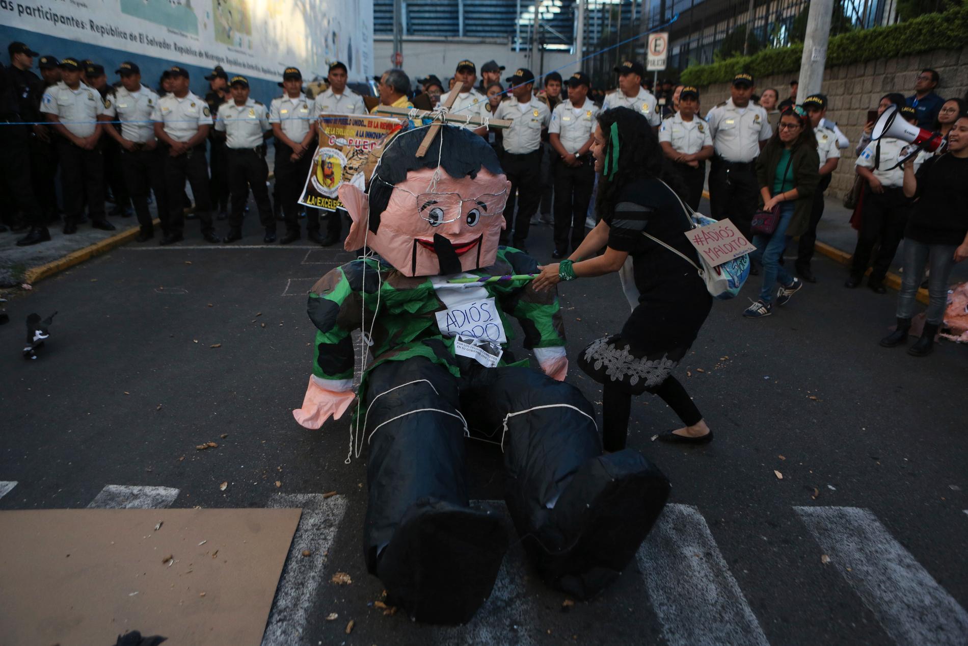 En demonstrant slår på en docka föreställande den avgående korruptionsanklagade presidenten Jimmy Morales under protester i huvudstaden Ciudad de Guatemala på tisdagen.