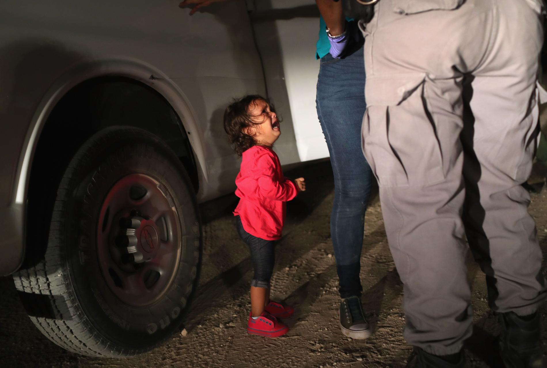 Bilden på en tvåårig honduransk flicka som gråter medan hennes mamma grips i Texas, USA, har fått stor spridning när migrationsdebatten rasar.