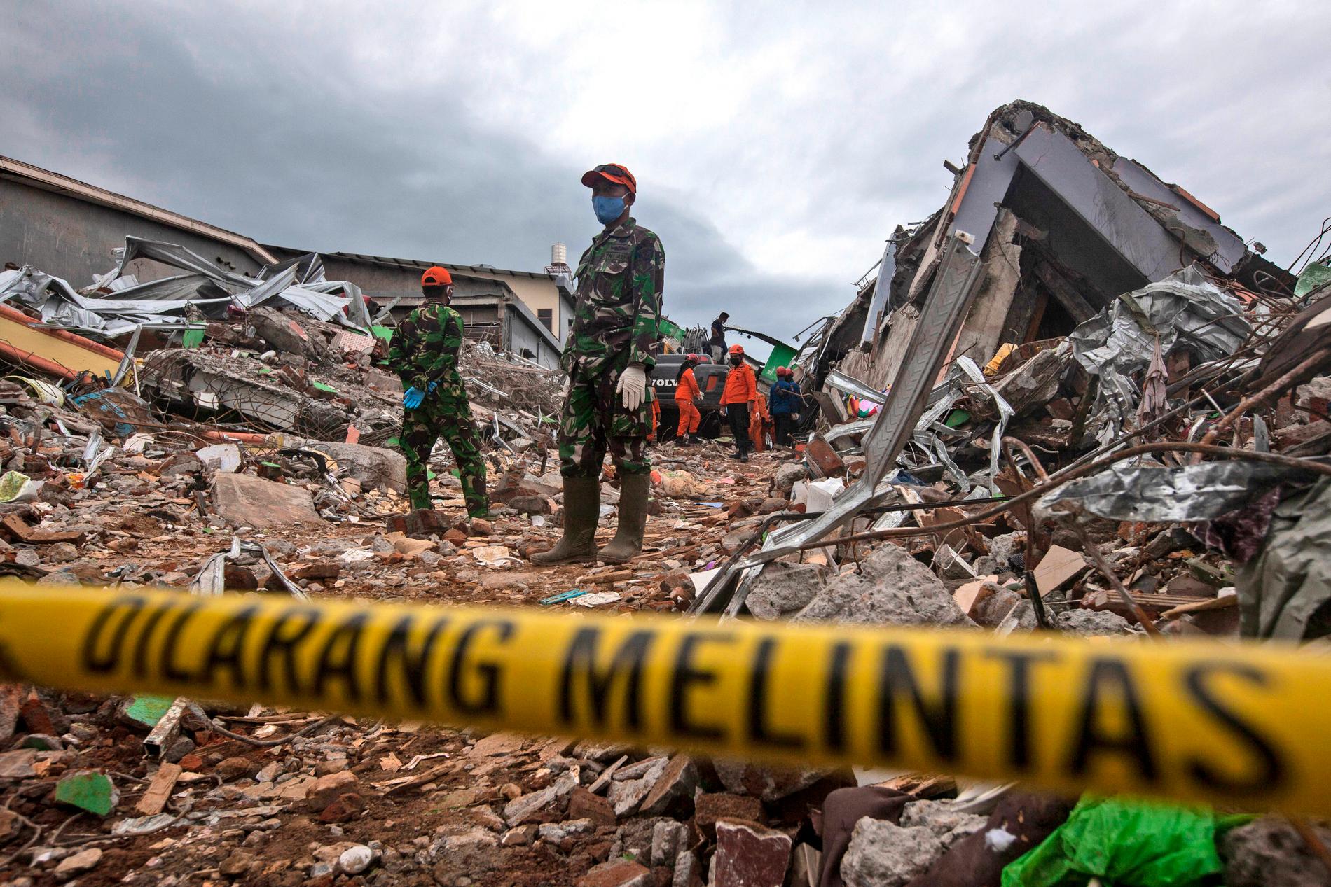 Räddningsarbetare letar efter offer i resterna av en kollapsad byggnad i Mamuju på västra Sulawesi i Indonesien.