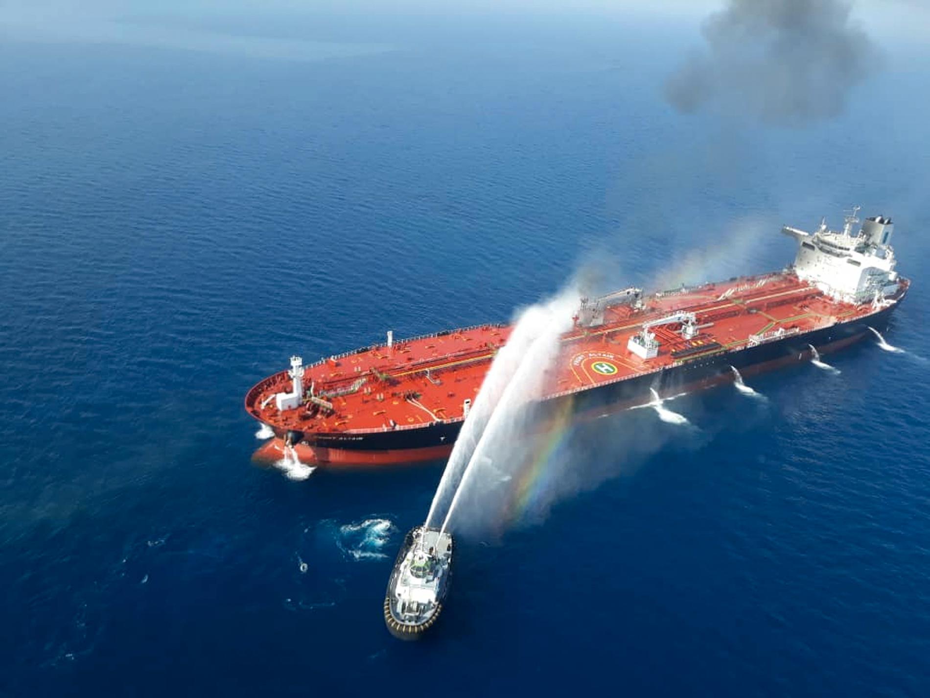 En båt från den iranska flottan i släckningsarbete vid ett av de attackerade fartygen. Bilden publicerades av den iranska nyhetsbyrån Tasnim.