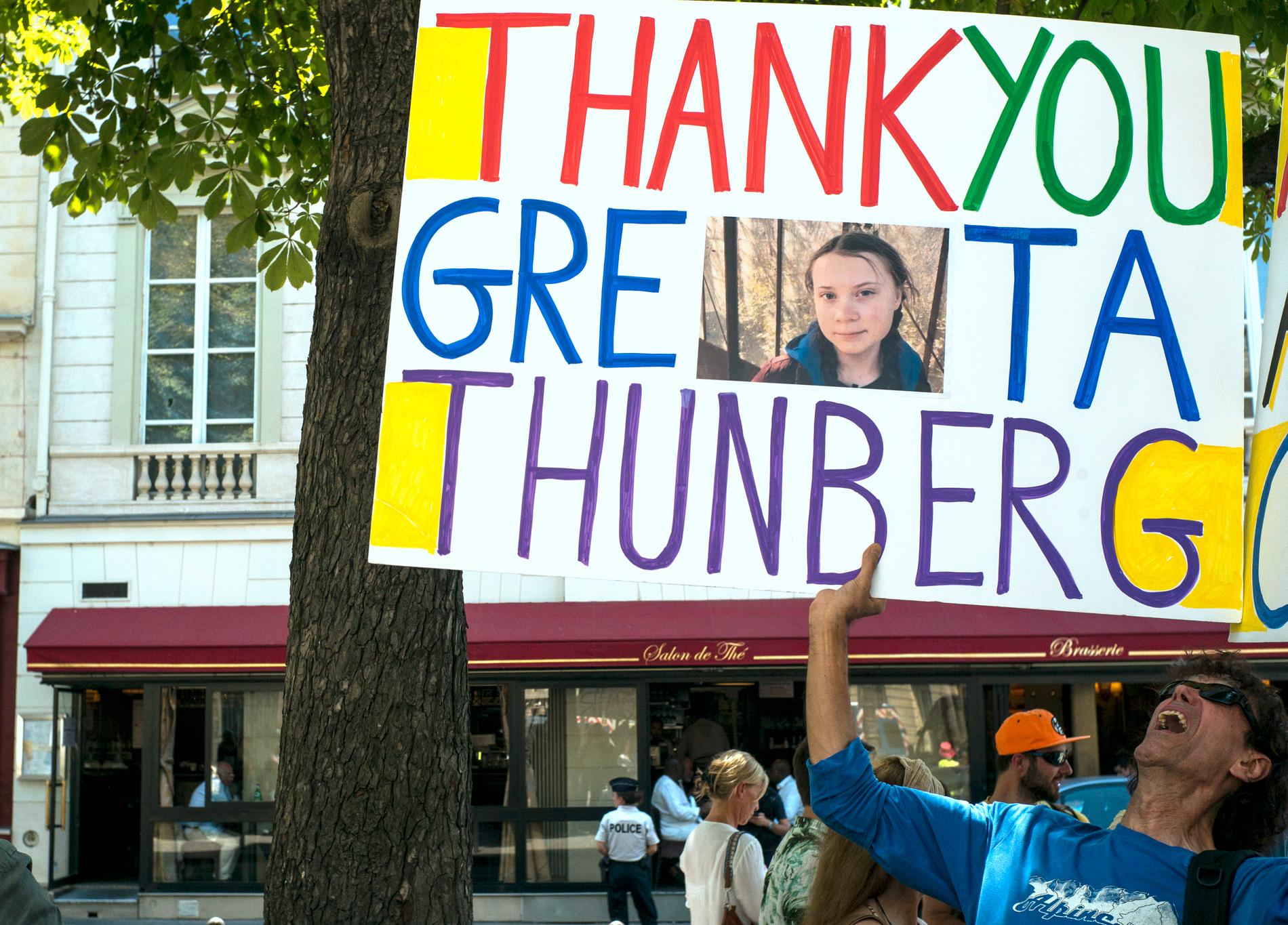 En man utanför nationalförsamlingen med ett plakat där han tackar Greta Thunberg.