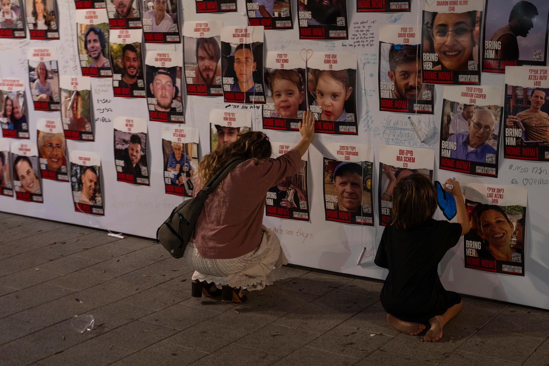 Bilder på israeler som saknas och hålls fångna i Gaza har satt upp på en vägg i Tel Aviv.