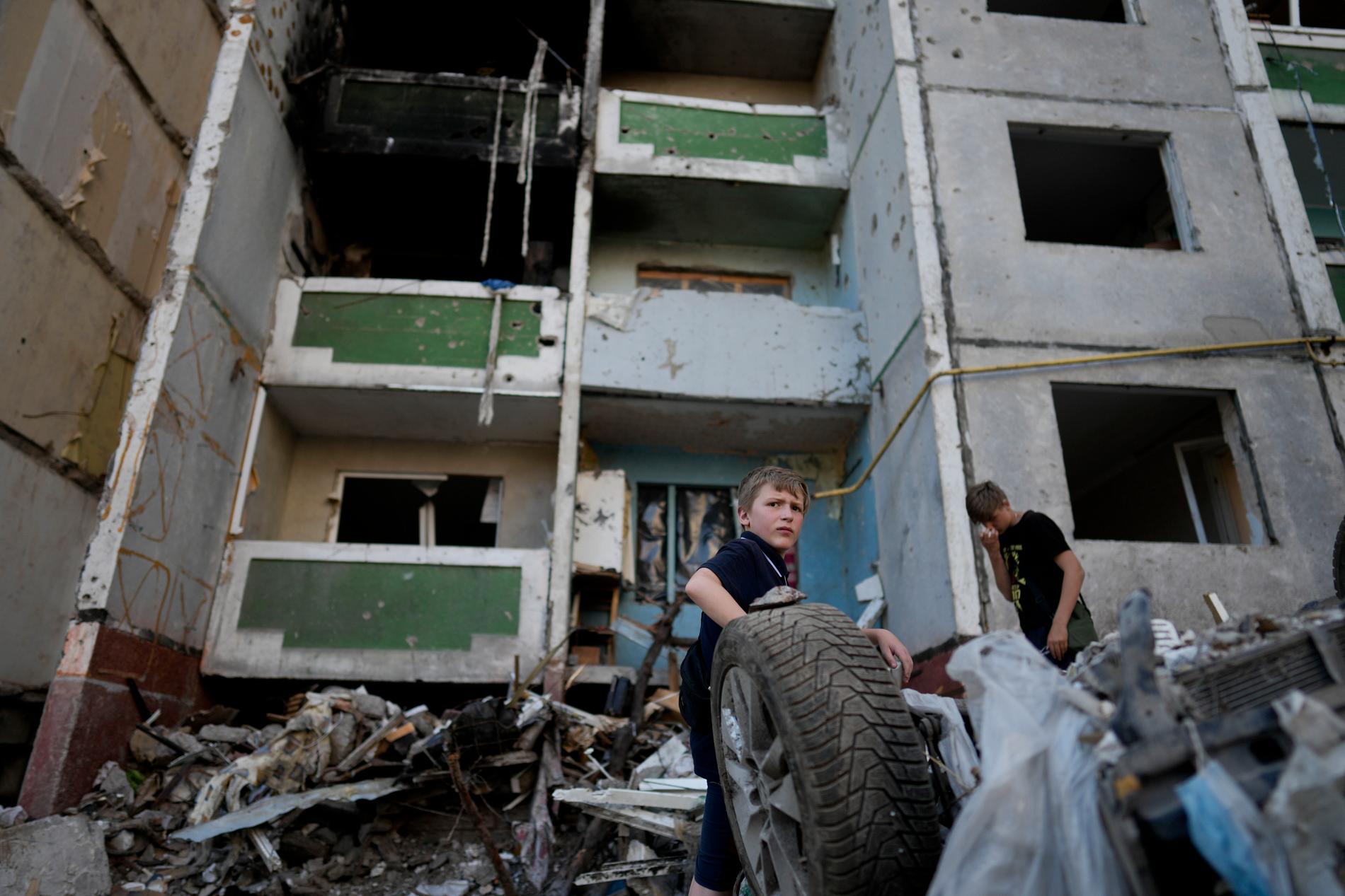 Barn framför en demolerad byggnad i Chernihiv, Ukraina på söndagen.