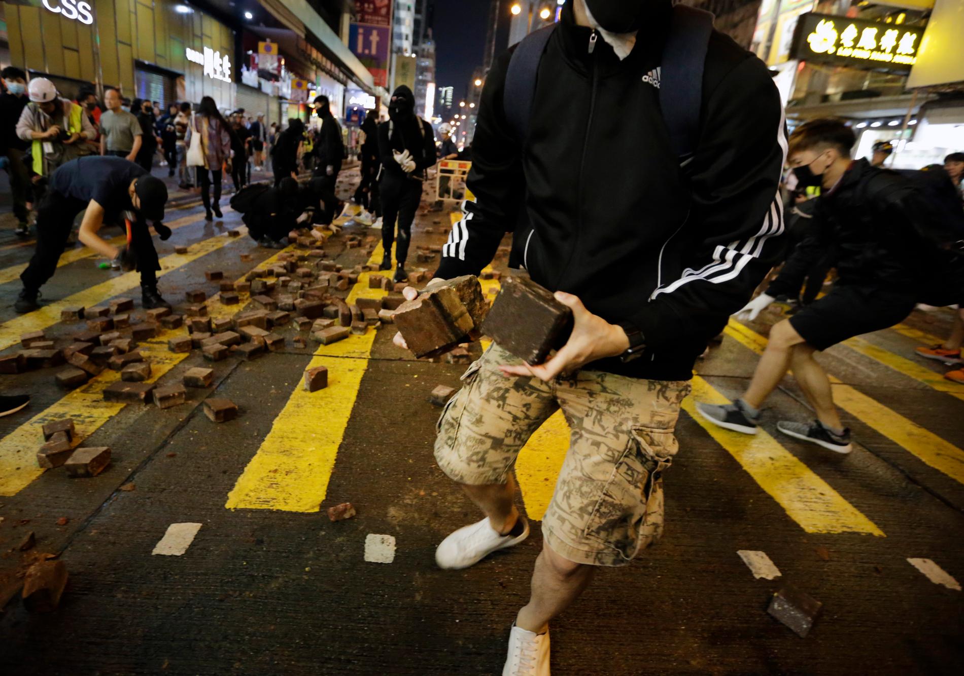 Demonstranter gräver upp gatstenar i Hongkong under söndagens nya protester i staden.