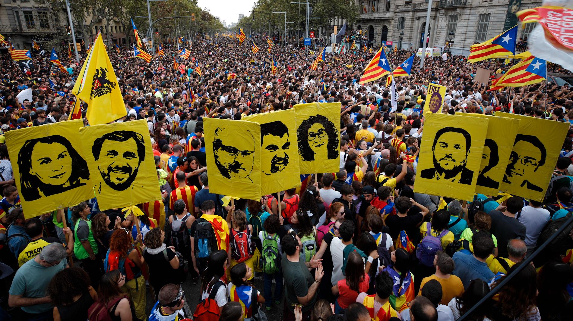 Demonstranter bär porträtt på dömda separatistledare under fredagens massprotest i Barcelona.