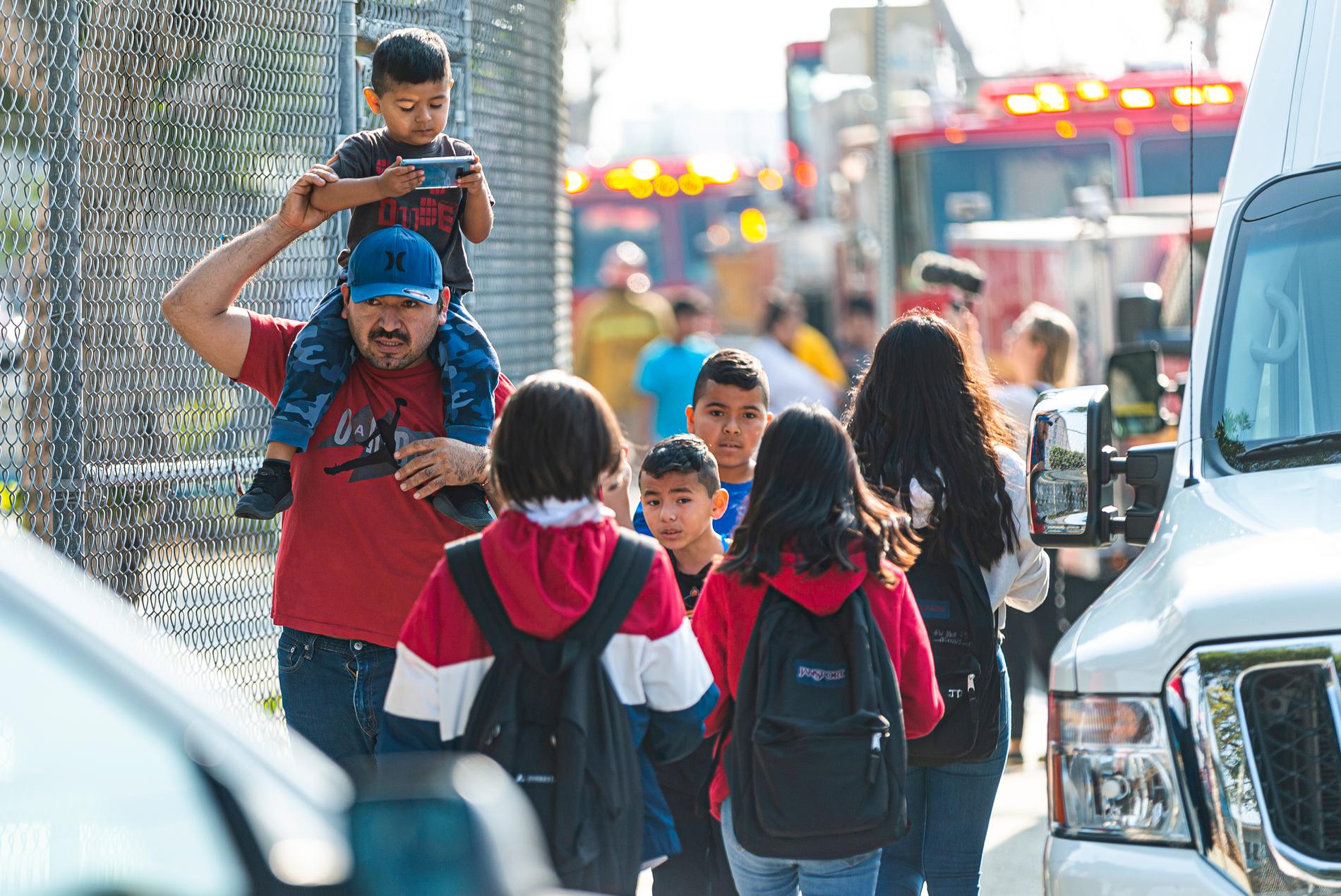 Barn evakueras efter att de och deras skola i stadsdelen Cudahy i Los Angeles fått flygbränsle släppt på sig.