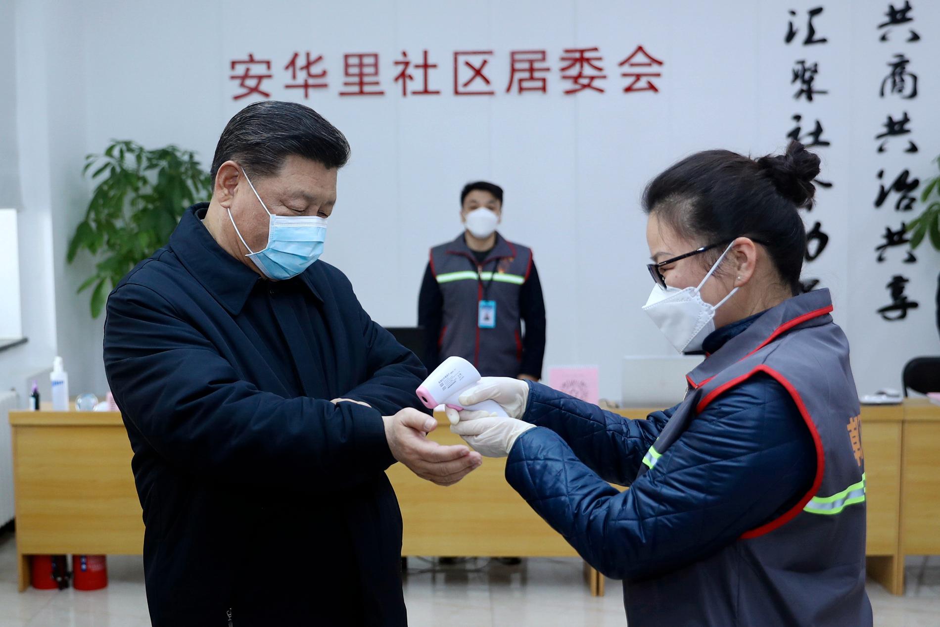 Kinas president Xi Jinping får temperaturen kontrollerad under ett besök på en vårdinrättning i Peking. Bild distribuerad av Kinas statliga nyhetsbyrå Nya Kina.