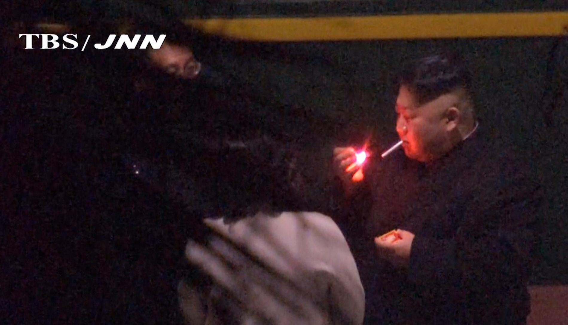 Kim Jong-Un tar en cigg på en tågstation i Kina, på väg mot Vietnam. Bild från japansk tv.