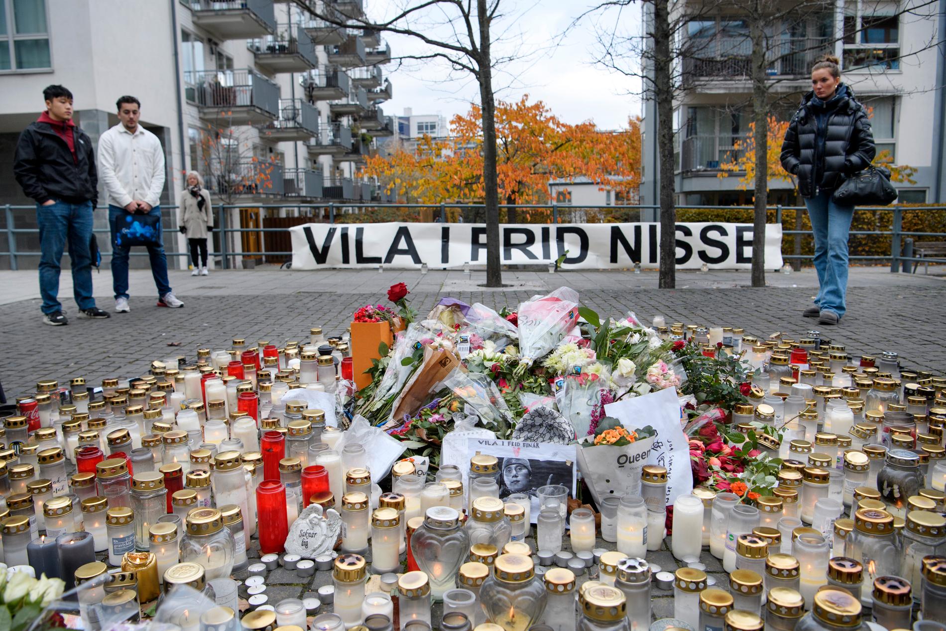 Blommor och ljus i närheten av platsen i Hammarby sjöstad i Stockholm där Nils Grönberg, mer känd som rapparen Einár, sköts till döds för en vecka sedan.