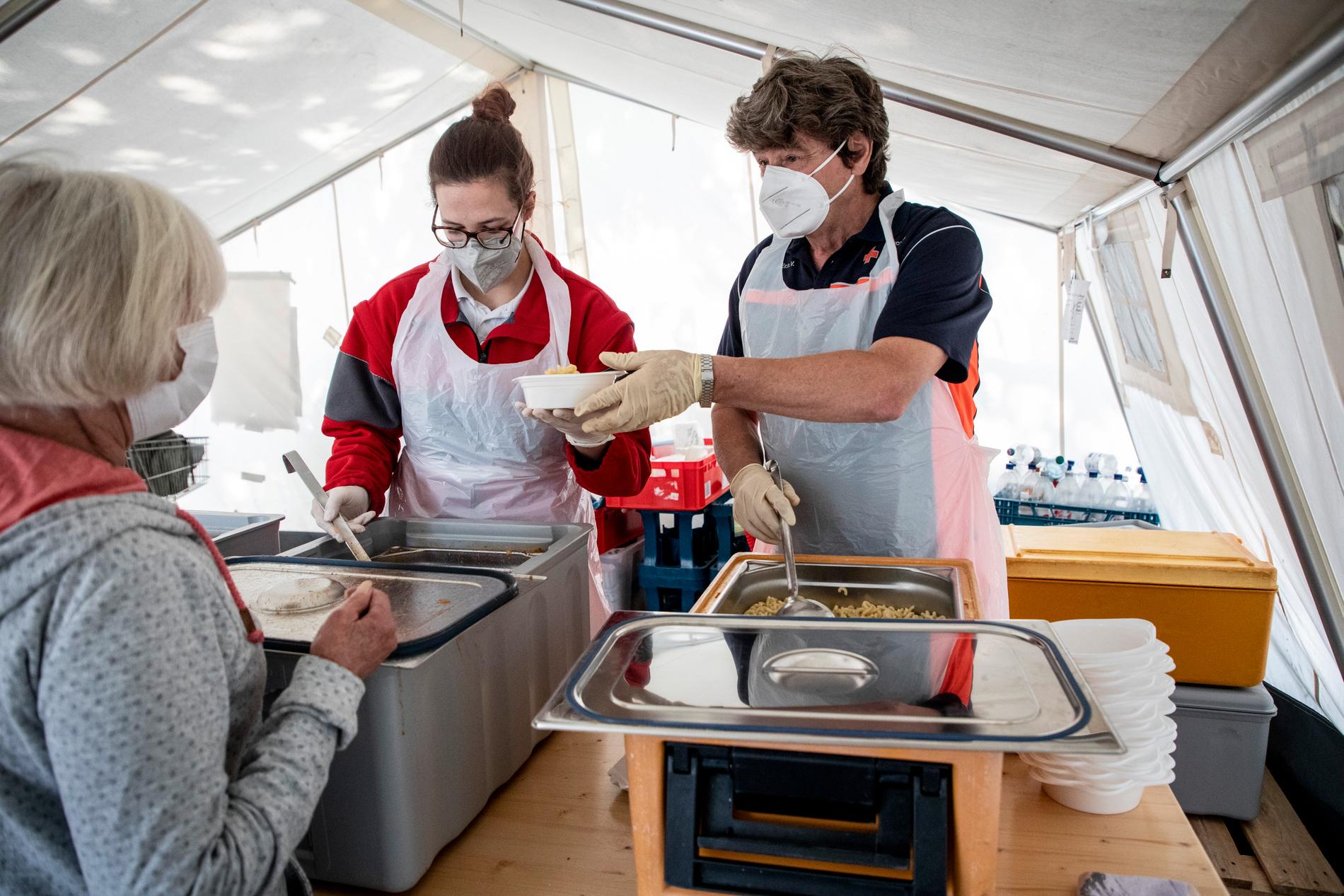 Patricia Schneider och Aurich Gert från Röda Korset serverar mat till invånare i Ahrweiler efter översvämningen.
