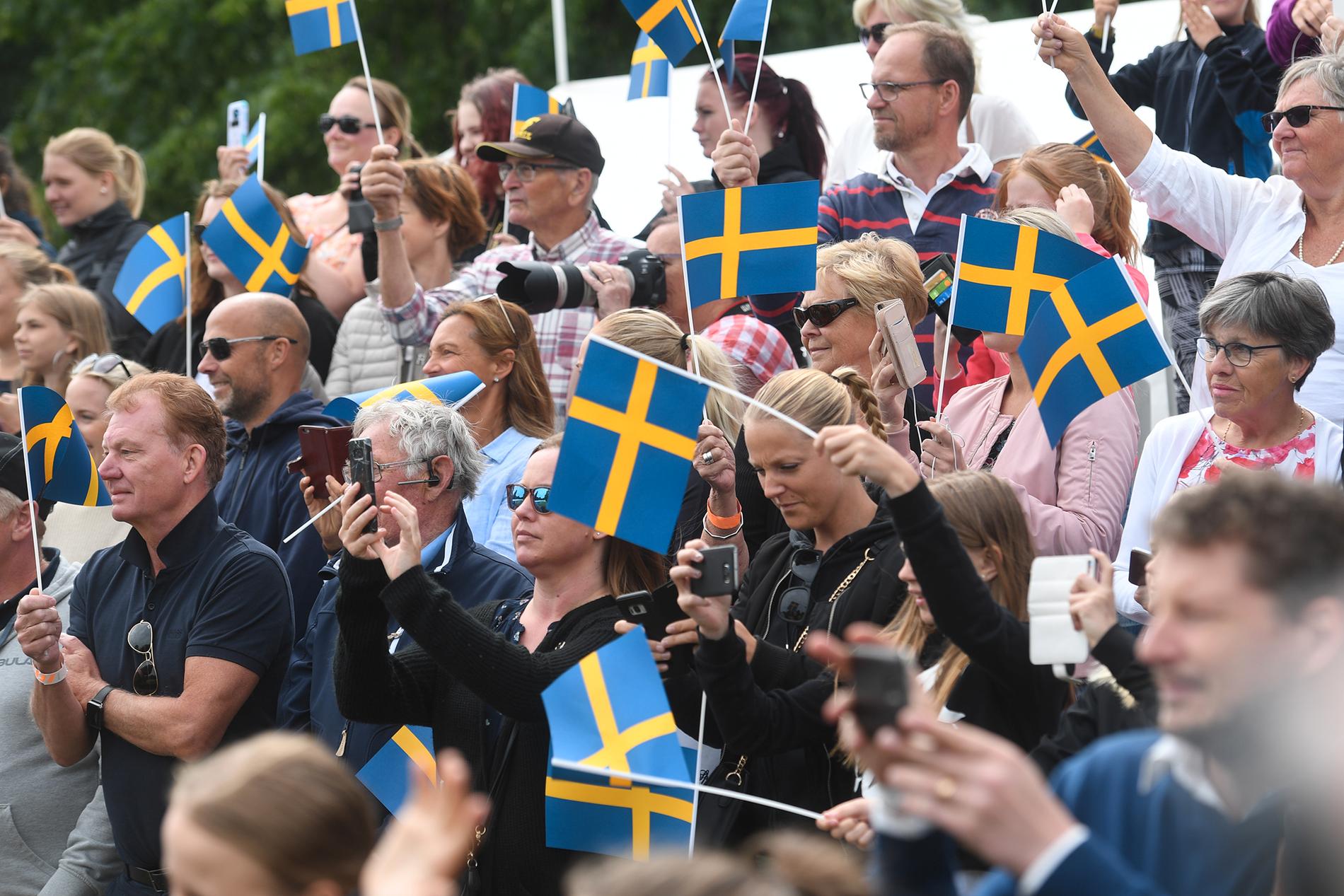 Åskådare med svenska flaggor då kronprinsessan Victoria och prins Daniel deltar i nationaldagsfirandet på Strömsholms slott.