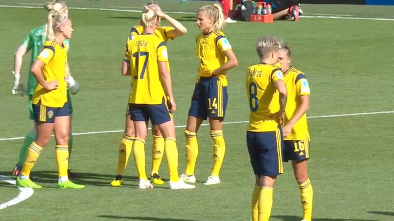 Svenska spelarna samlas i grupper vid avbrott i matchen. 