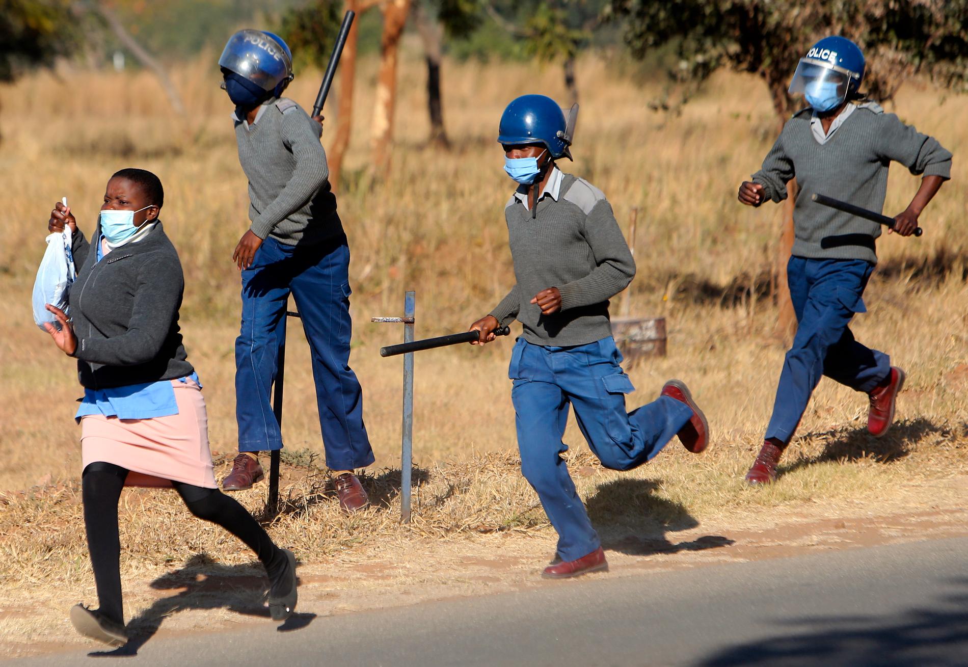 Poliser jagar en av de demonstrerande sjuksköterskorna i Zimbabwes huvudstad Harare.