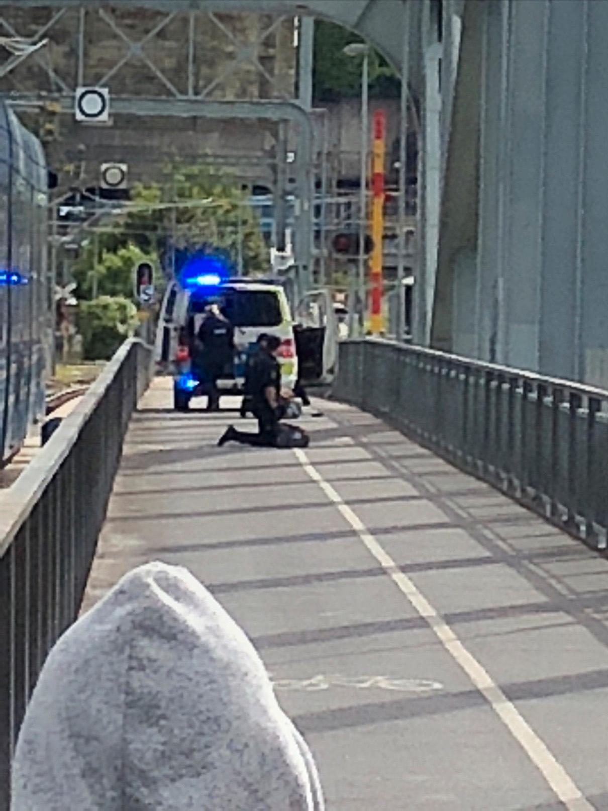 En person grips på en gångbro efter skjutningen. 