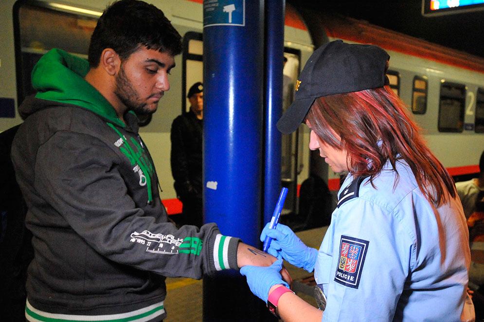En flykting märks med spritpenna på armen av en polis i Tjeckien.