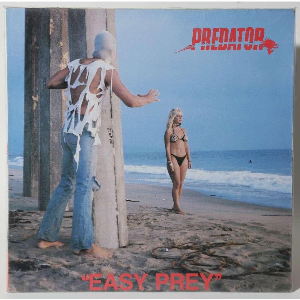 Predator - Easy Prey Orkestern Predator försökte sig på att sälja skivor med en maskerad man (med en jättekonstig t-shirt) lurpassande på en inte ont anande kvinna på strandpromenad.
