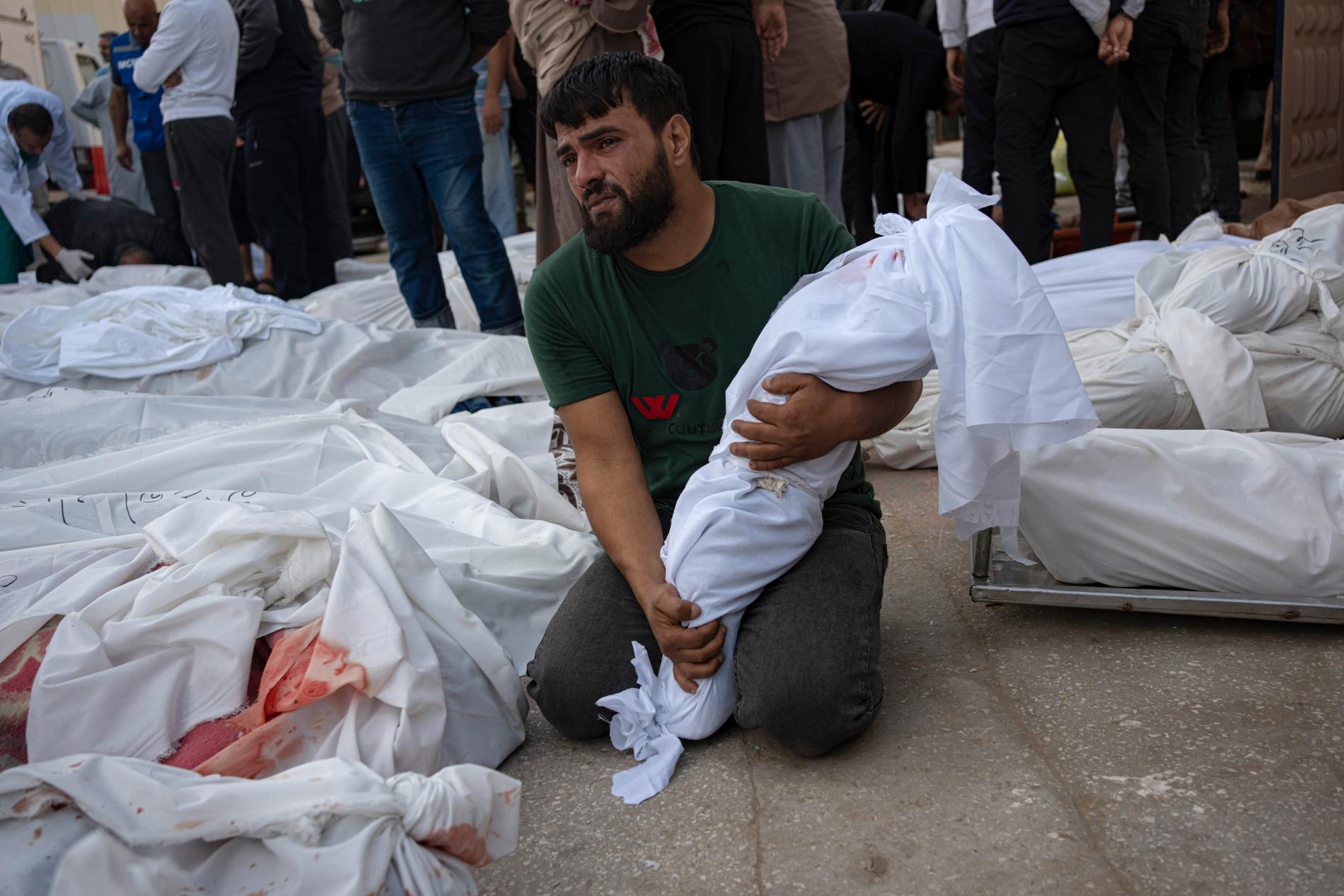 En palestinsk man håller sitt döda barns kropp efter attacker mot Gaza.