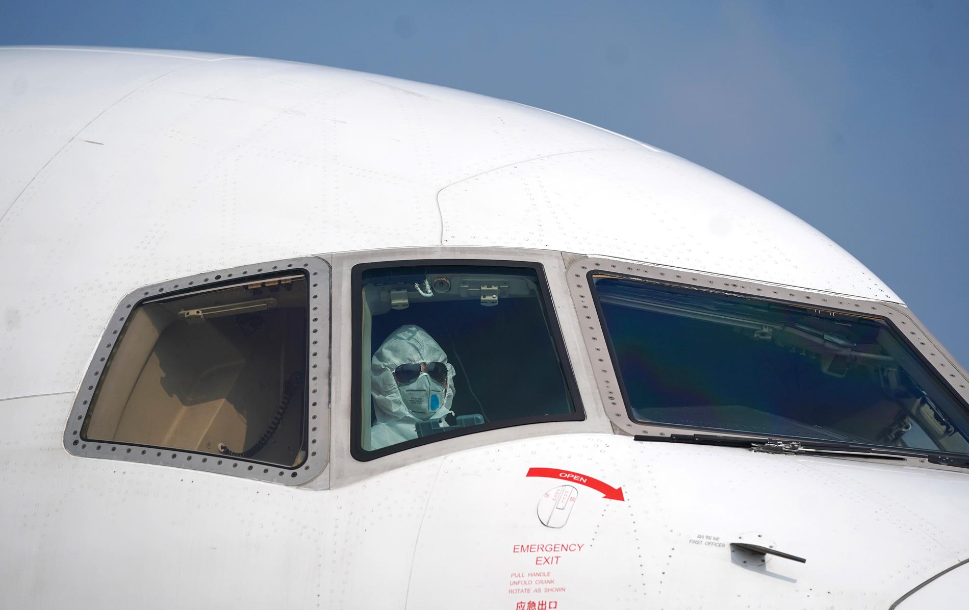 En pilot iförd skyddskläder parkerar ett flygplan på Wuhans flygplats Tianhe på tisdagen.