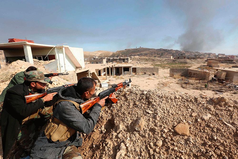 Krigare ur kurdiska peshmerga-styrkor positionerar sig i staden Sinjar.