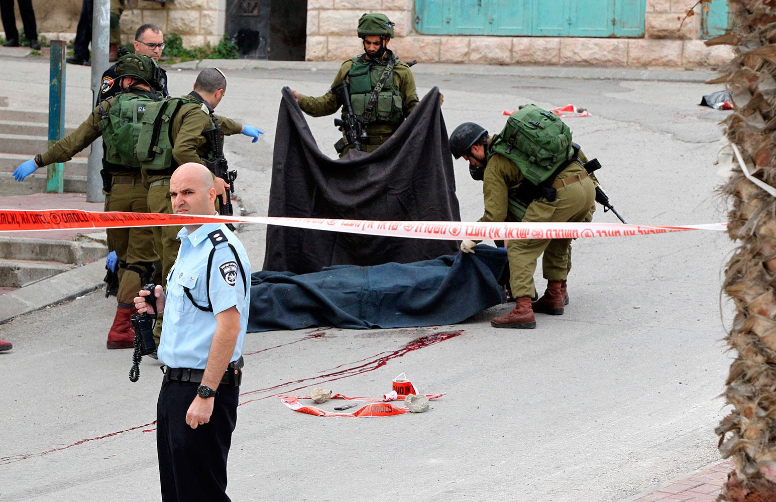 Soldater täcker över den palestinske mannen strax efter att han skjutits.