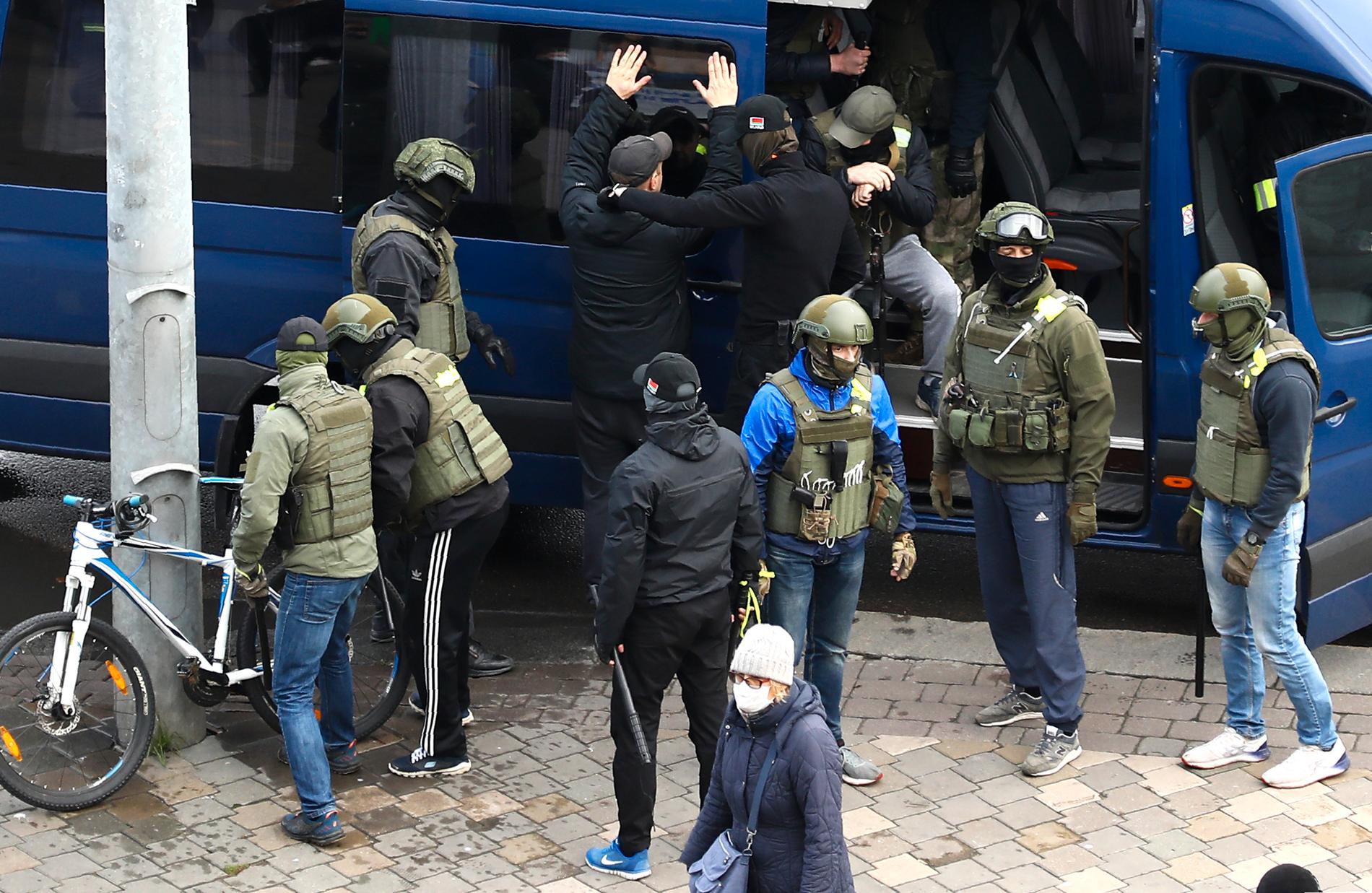 Polismakten, som ibland är militärt uniformerad och ibland klär sig mer civilt, har gripit tusentals människor och fört bort dem i bussar. Här har en man på cykel stoppats i Minsk den 8 november, varpå han placeras i en sådan buss. Arkivbild.