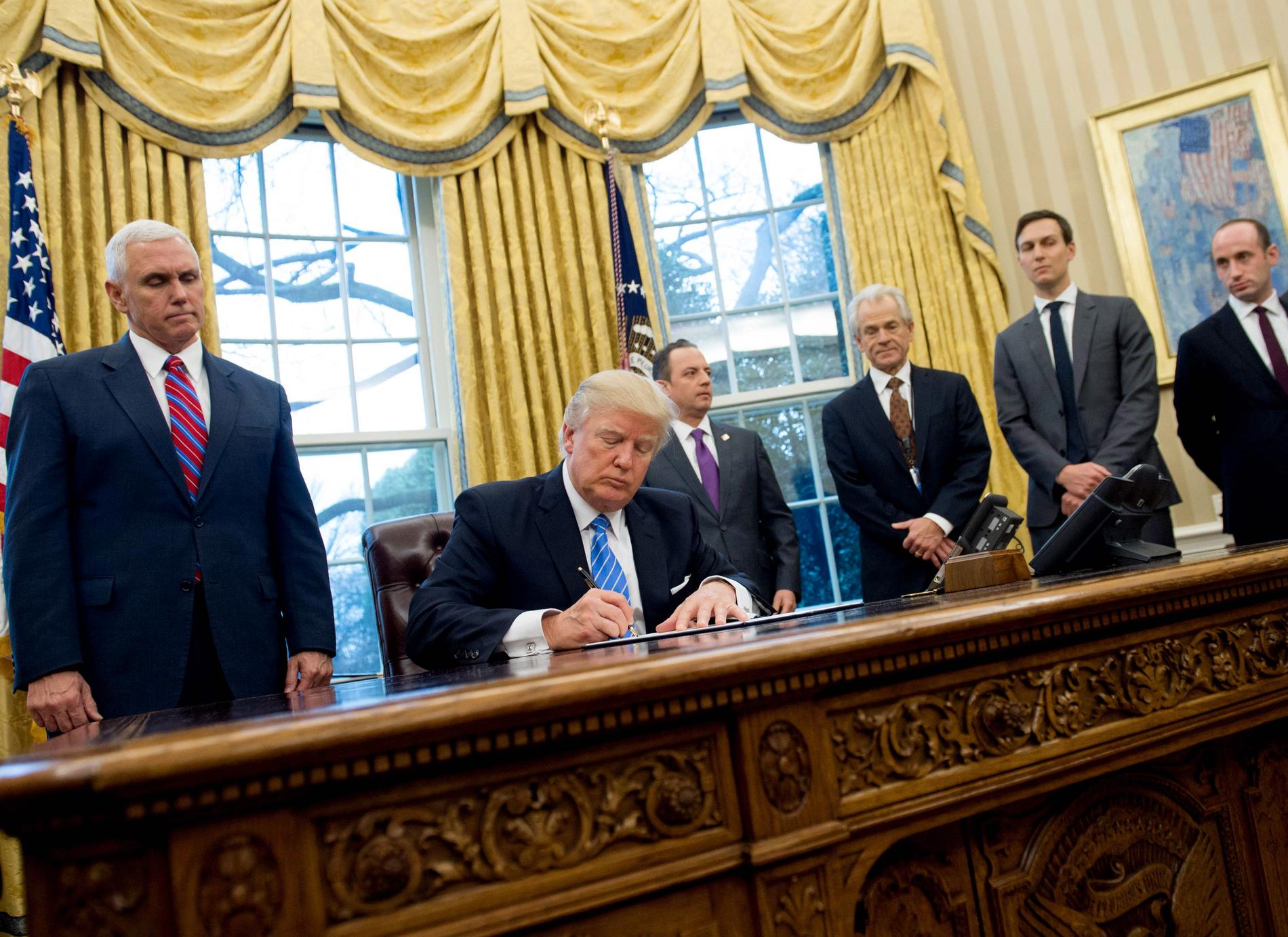 Stephen Miller, längst till höger, tittar på när Trump skriver under en exekutiv order i Vita huset