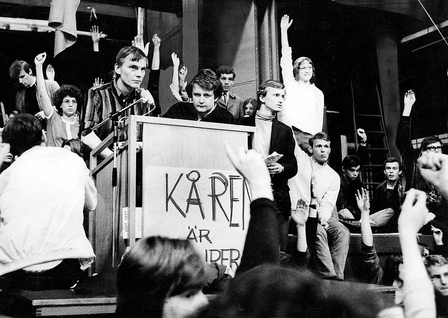 Studenter vid Stockholms universitet ockuperar kårhuset i maj 1968 i en protest mot en ny studieförordning. I talarstolen syns Anders Carlberg, ordförande för ockupationen.