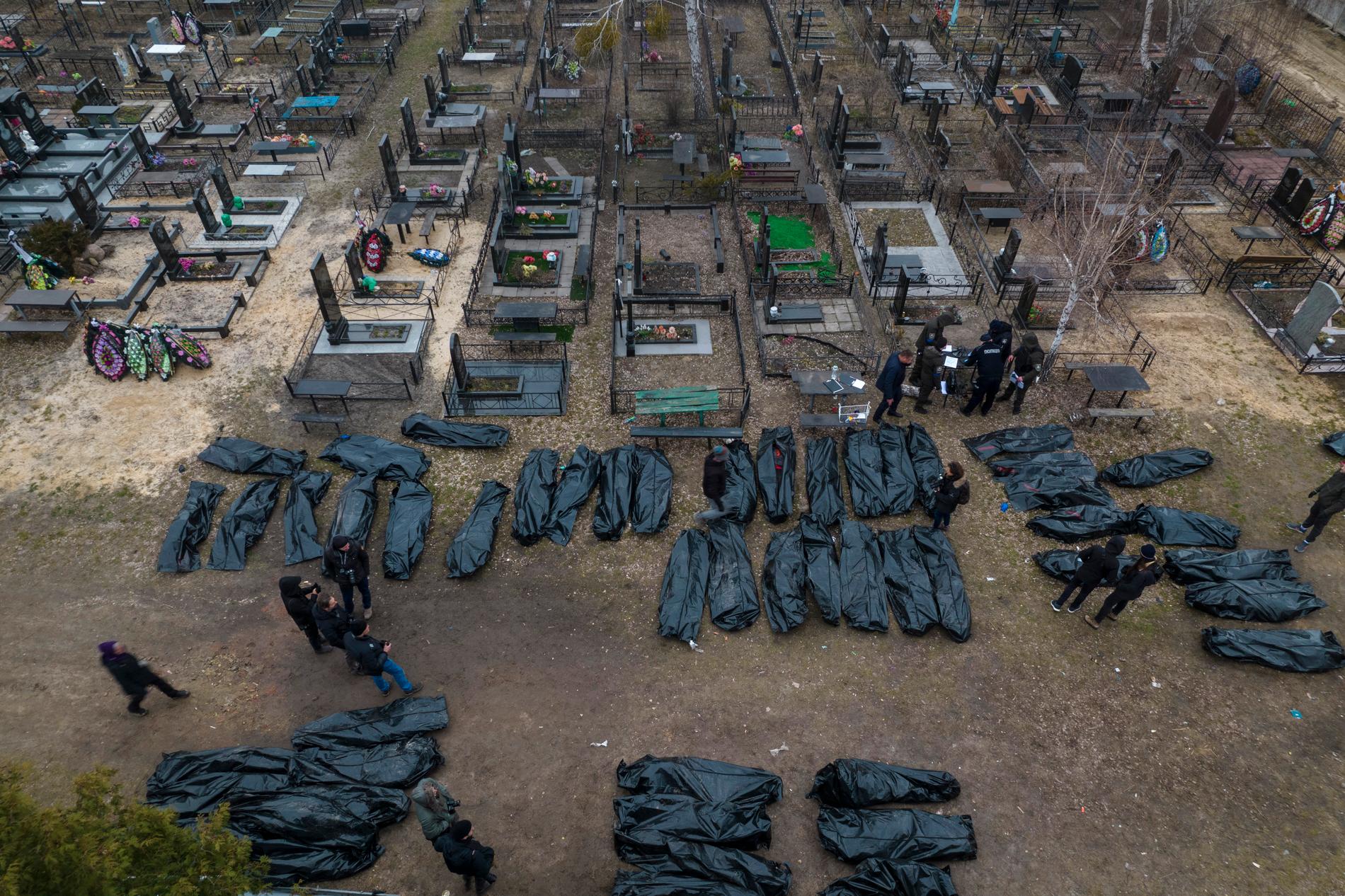Ukrainsk polis undersöker döda civila innan de begravs i Kiev på onsdagen.