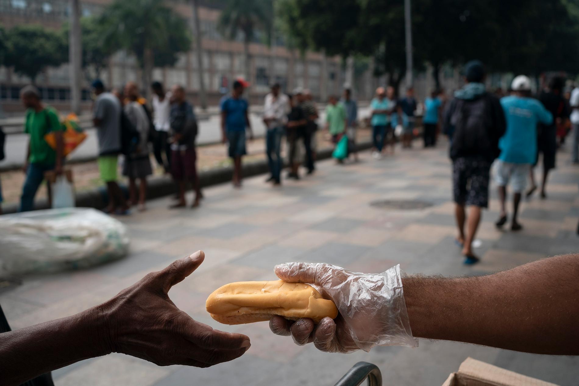 I Rio de Janeiro håller sig de allra flesta människor hemma, men hemlösa bildar långa köer för att få mat från en privat välgörenhetsorganisation.