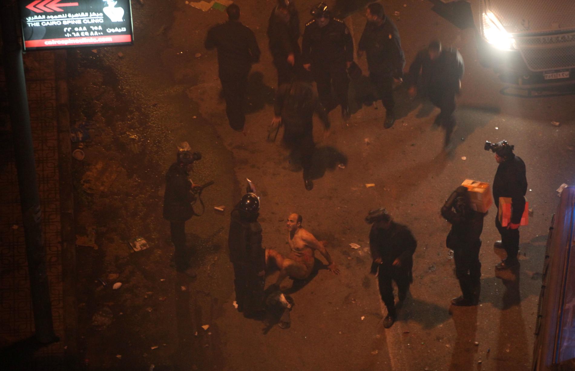 Kravallpolis misshandlar en av demonstranterna efter att först ha slitit av honom hans kläder.