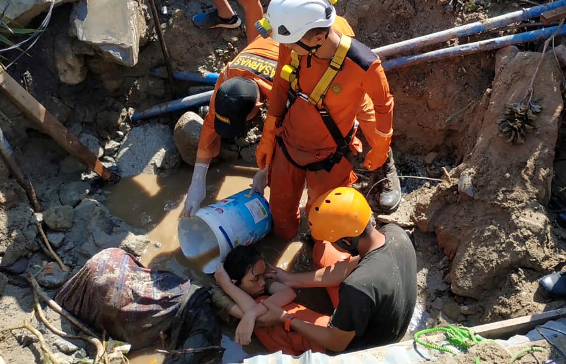 Räddningspersonal hjälper en person som sitter fast efter jordbävningen och tsunamin som drabbade Indonesien.