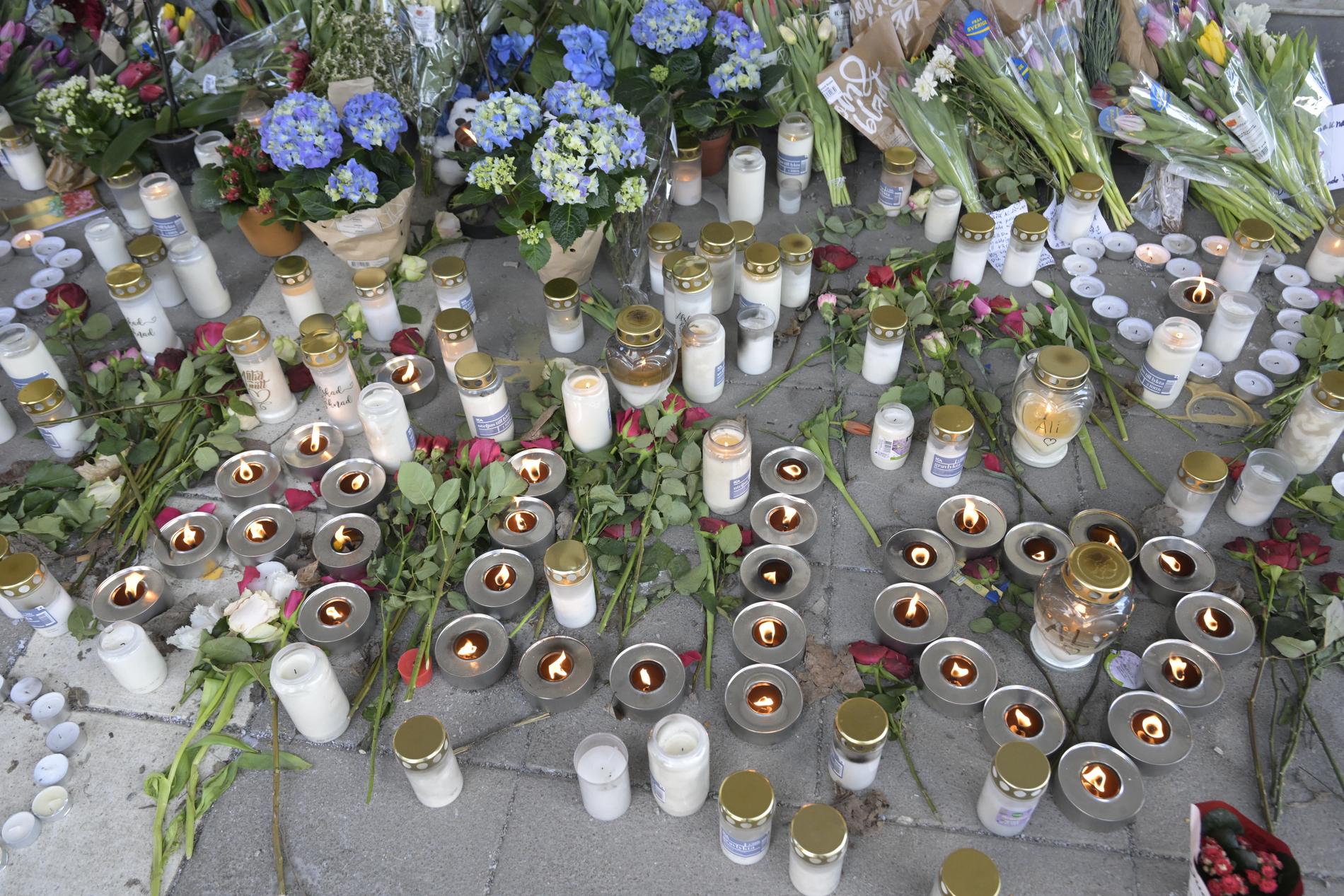 Blommor och ljus i närheten av mordplatsen i Skogås Centrum i södra Stockholm, där en 15-årig pojke sköts ihjäl inne på en restaurang den 28 januari. Arkivbild.