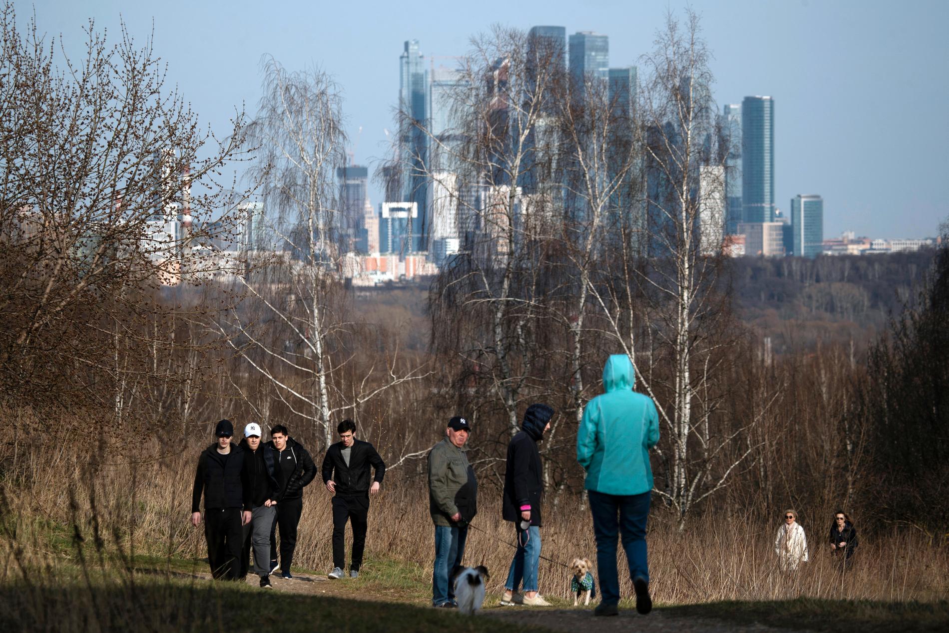 Moskva tycks än så länge bara stå i en sluttning. Här promenerar några av stadens invånare i en park på torsdagen, trots strikta påbud om att stanna hemma.